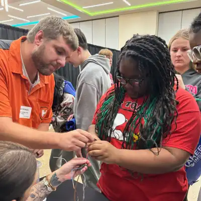 Image of a volunteer showing a student a machine